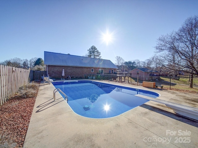 view of swimming pool with a diving board and a patio