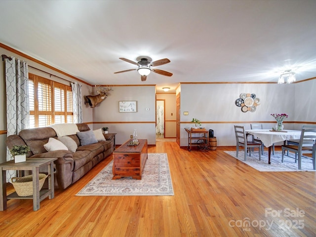 living room featuring crown molding, ceiling fan, and light hardwood / wood-style floors