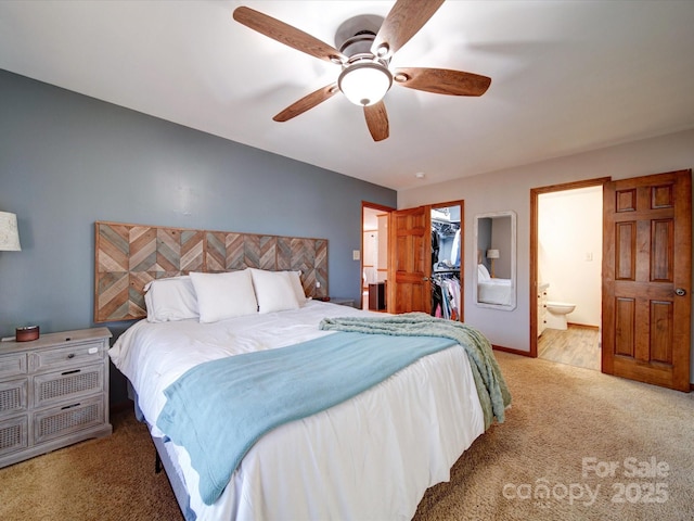 carpeted bedroom with connected bathroom, a walk in closet, a closet, and ceiling fan