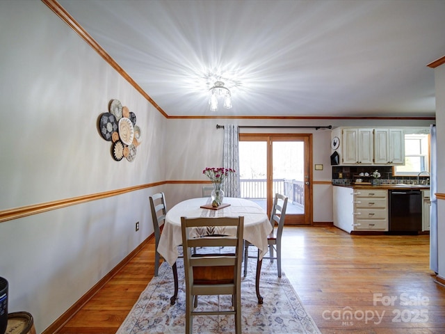 dining room featuring sink, crown molding, and light hardwood / wood-style flooring