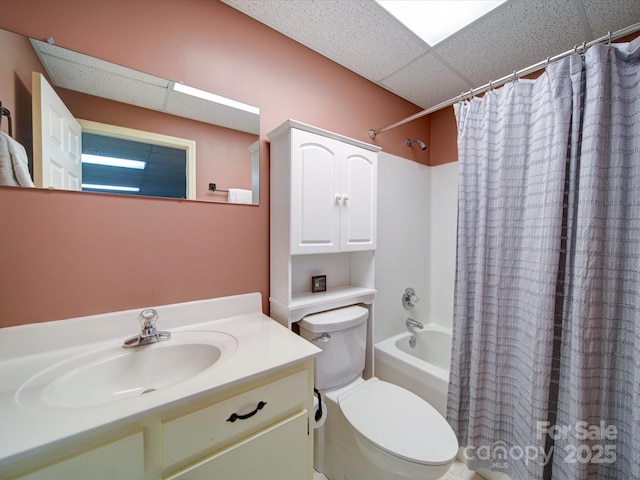 full bathroom featuring a drop ceiling, vanity, toilet, and shower / bathtub combination with curtain