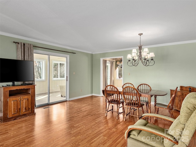 dining room featuring light hardwood / wood-style floors, crown molding, and an inviting chandelier