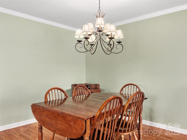 dining area with hardwood / wood-style flooring, crown molding, and an inviting chandelier