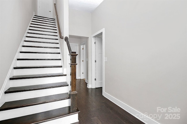 stairway with hardwood / wood-style floors and a towering ceiling