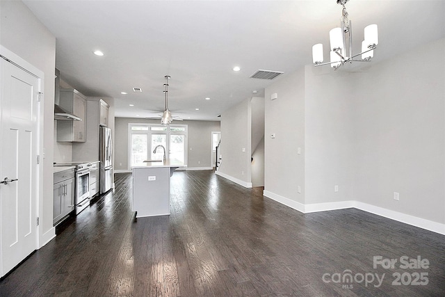 kitchen featuring gray cabinetry, stainless steel appliances, sink, a center island with sink, and hanging light fixtures