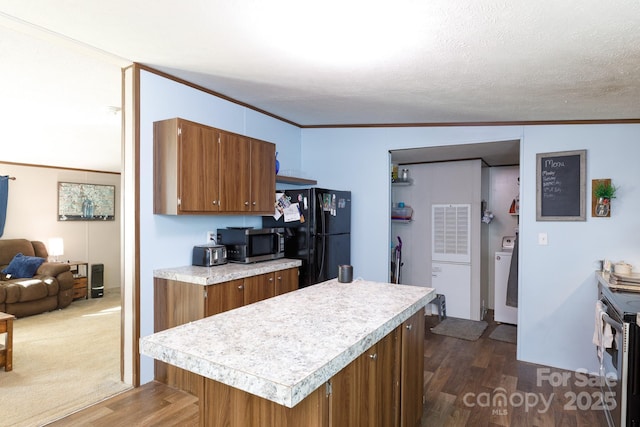 kitchen featuring dark hardwood / wood-style flooring, vaulted ceiling, a textured ceiling, black refrigerator, and ornamental molding