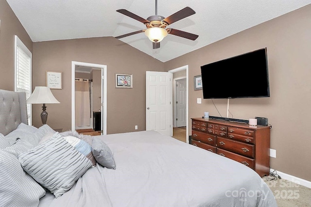 carpeted bedroom featuring ceiling fan, ensuite bathroom, and vaulted ceiling