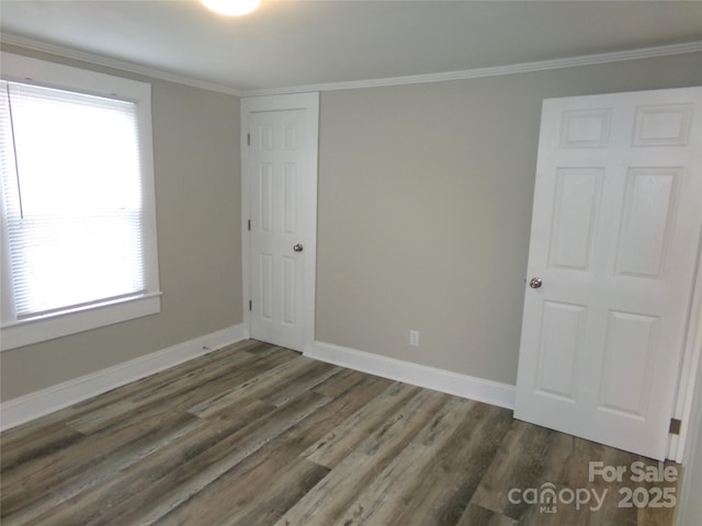 spare room with crown molding and dark wood-type flooring