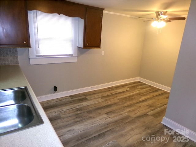 interior space featuring decorative backsplash, ceiling fan, dark wood-type flooring, and sink