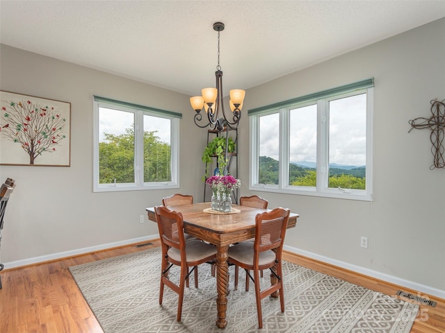 dining area featuring hardwood / wood-style flooring and an inviting chandelier