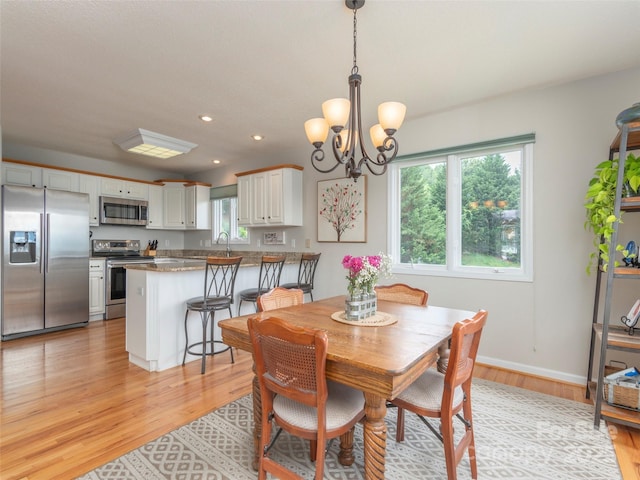 dining area featuring a healthy amount of sunlight, light hardwood / wood-style flooring, a notable chandelier, and sink