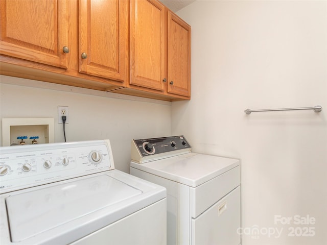 clothes washing area with separate washer and dryer and cabinets