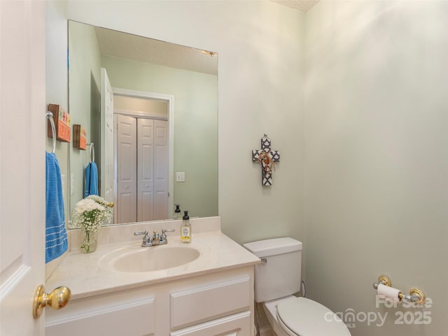 bathroom with a textured ceiling, vanity, and toilet