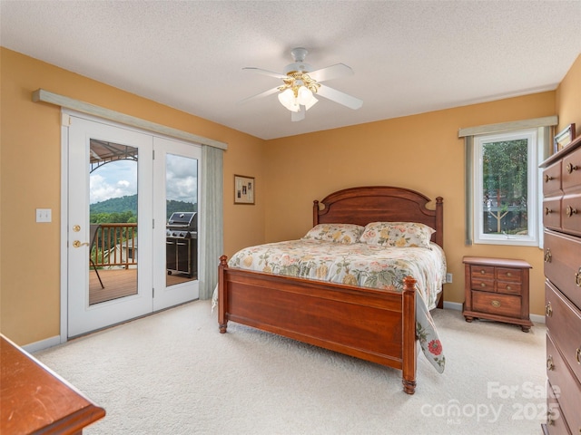 bedroom with ceiling fan, access to exterior, light colored carpet, and a textured ceiling