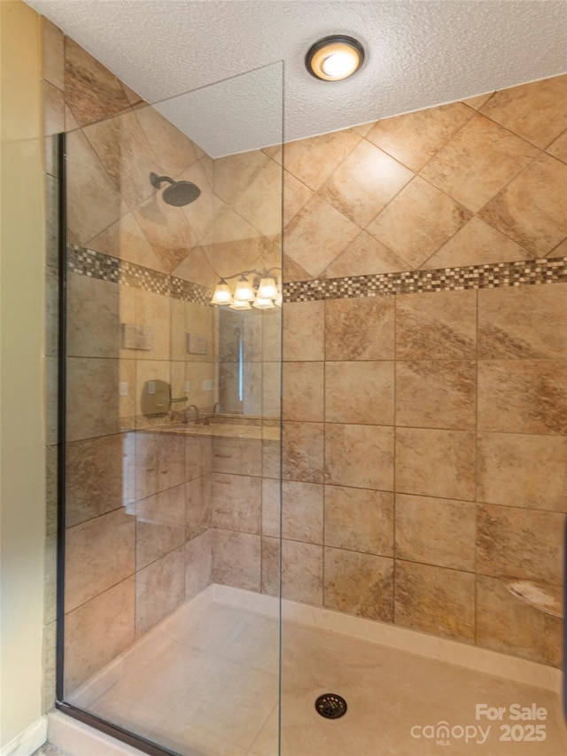 bathroom with a textured ceiling and tiled shower