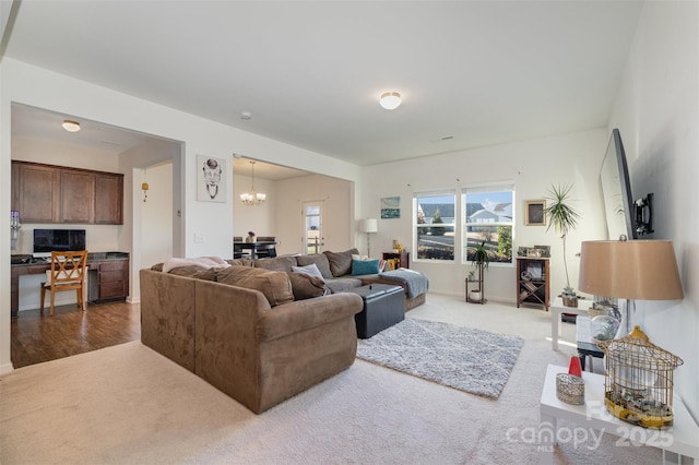 living room with a chandelier, carpet floors, and built in desk