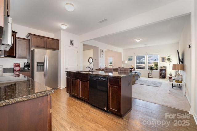 kitchen with dishwasher, sink, light hardwood / wood-style flooring, stainless steel refrigerator with ice dispenser, and a kitchen island with sink