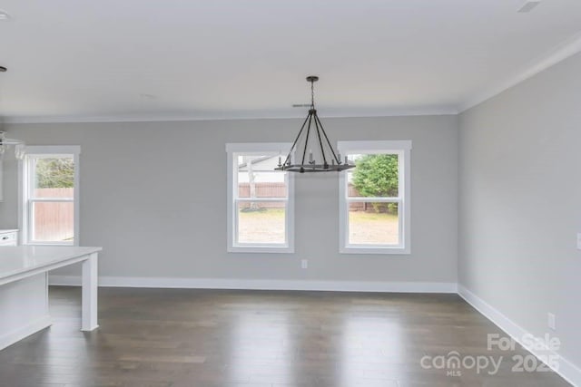 unfurnished dining area featuring a notable chandelier, dark hardwood / wood-style floors, crown molding, and a wealth of natural light