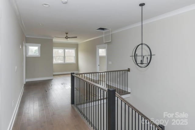 corridor with crown molding, hardwood / wood-style floors, and a chandelier