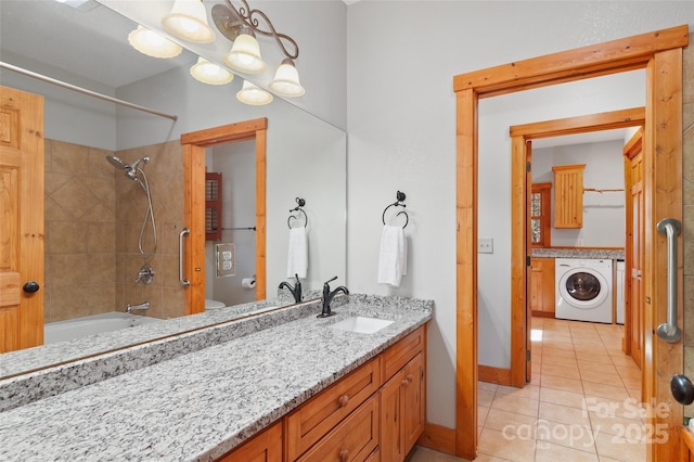 bathroom featuring tiled shower / bath, vanity, washer / dryer, and tile patterned flooring