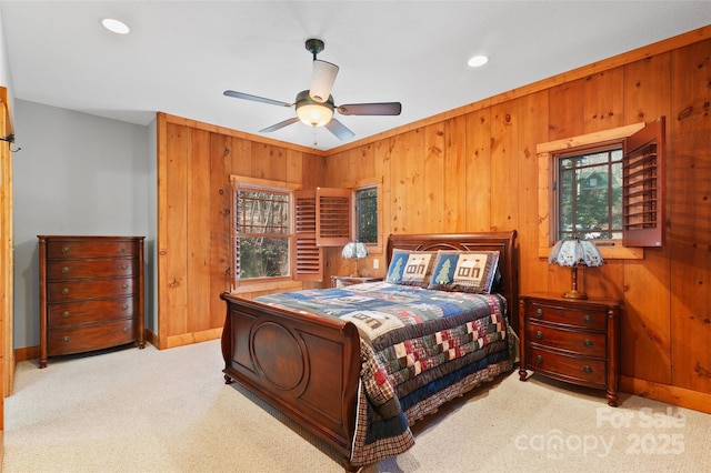 bedroom with ceiling fan, light carpet, and wood walls