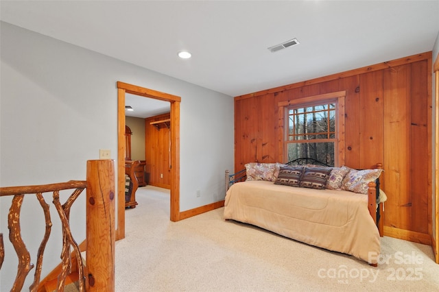 bedroom with light colored carpet and wood walls