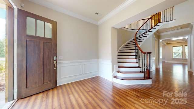 foyer with wood-type flooring and crown molding