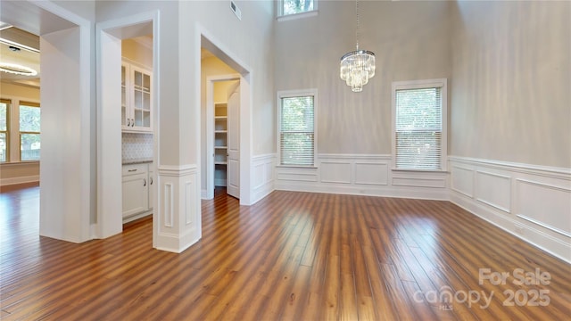 unfurnished dining area with a notable chandelier and dark hardwood / wood-style flooring