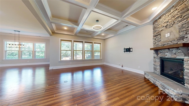 unfurnished living room with coffered ceiling, ornamental molding, a fireplace, beamed ceiling, and a notable chandelier