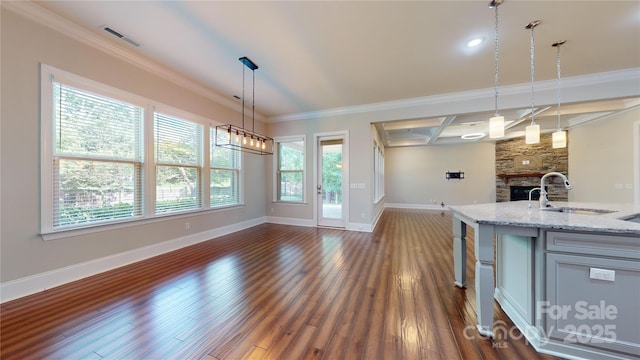 kitchen featuring light stone countertops, sink, coffered ceiling, crown molding, and pendant lighting