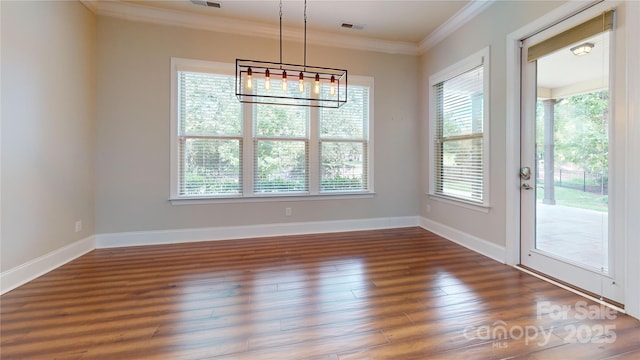 unfurnished dining area with dark hardwood / wood-style floors, ornamental molding, and a notable chandelier