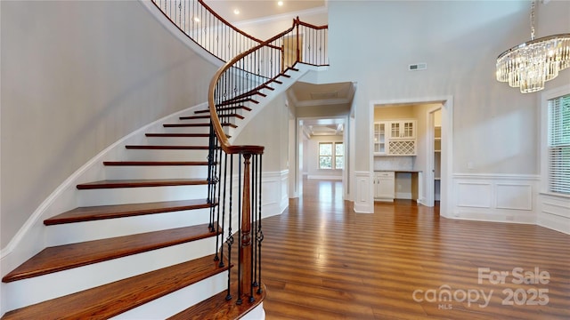 staircase featuring crown molding, hardwood / wood-style floors, and a notable chandelier