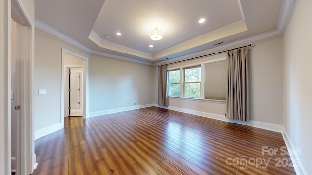 empty room featuring dark hardwood / wood-style flooring, a tray ceiling, and ornamental molding