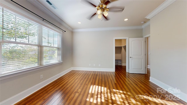 unfurnished bedroom with a closet, a spacious closet, ceiling fan, and ornamental molding