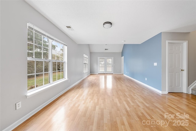 unfurnished room featuring lofted ceiling and light wood-type flooring