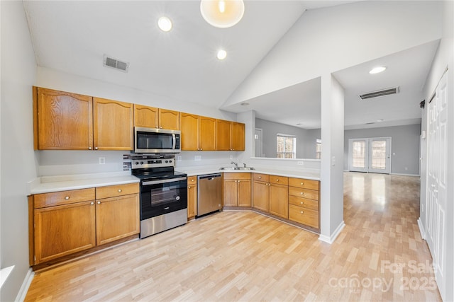 kitchen with sink, light hardwood / wood-style flooring, high vaulted ceiling, and appliances with stainless steel finishes