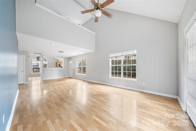 unfurnished living room with ceiling fan, high vaulted ceiling, and light hardwood / wood-style flooring