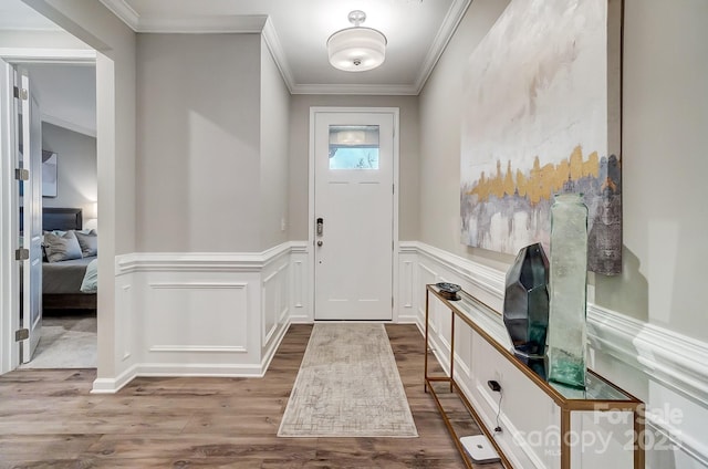 foyer entrance with ornamental molding and light wood-type flooring