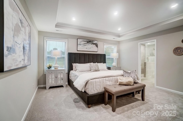 bedroom featuring ensuite bath, light colored carpet, and a tray ceiling