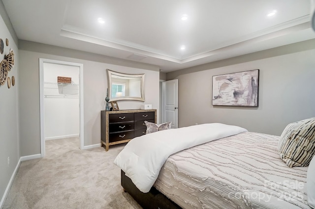 carpeted bedroom featuring a closet, a walk in closet, and a raised ceiling