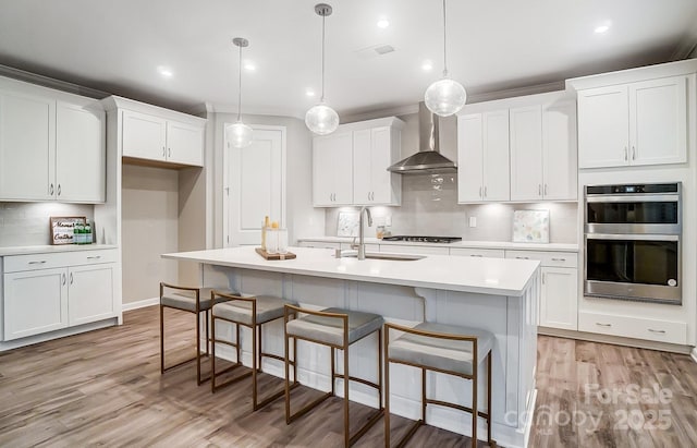 kitchen with decorative light fixtures, wall chimney range hood, decorative backsplash, and stainless steel double oven