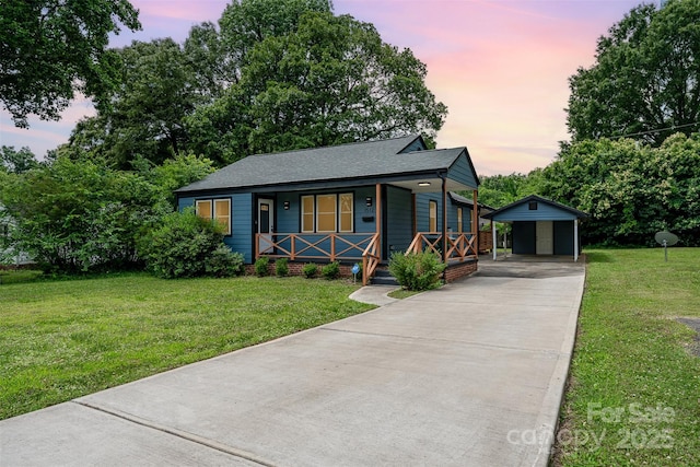 view of front of property with a porch, a garage, an outbuilding, and a yard