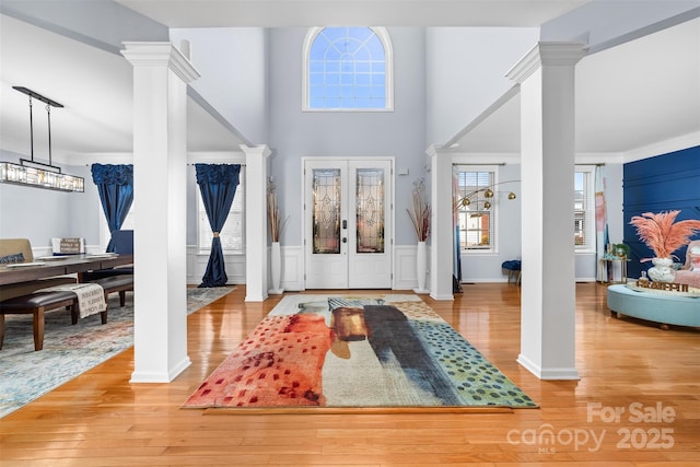 foyer entrance with french doors, light hardwood / wood-style flooring, and decorative columns