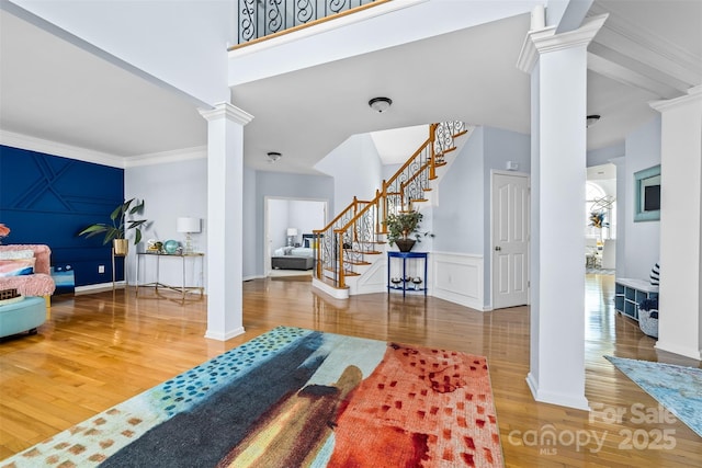 entryway with ornamental molding, hardwood / wood-style floors, and decorative columns