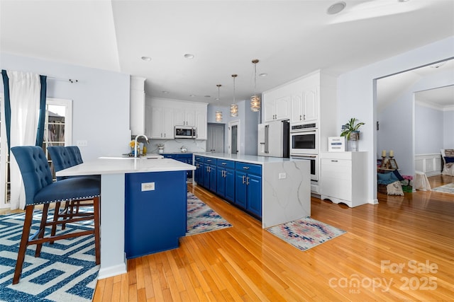 kitchen with white cabinets, an island with sink, appliances with stainless steel finishes, and blue cabinets