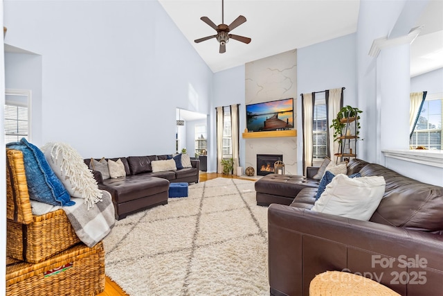 living room with high vaulted ceiling, a large fireplace, and ceiling fan