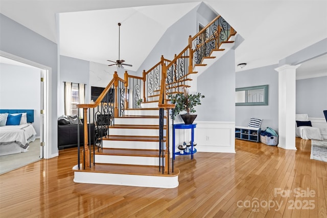 stairs featuring decorative columns, wood-type flooring, ceiling fan, and vaulted ceiling