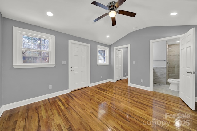 unfurnished bedroom with ceiling fan, ensuite bathroom, multiple windows, and lofted ceiling