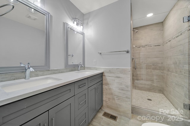 bathroom with tile patterned floors, vanity, an enclosed shower, and tile walls