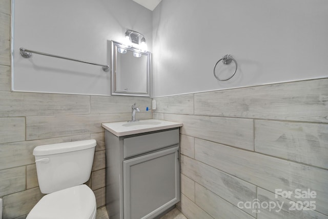 bathroom featuring vanity, tile walls, and toilet